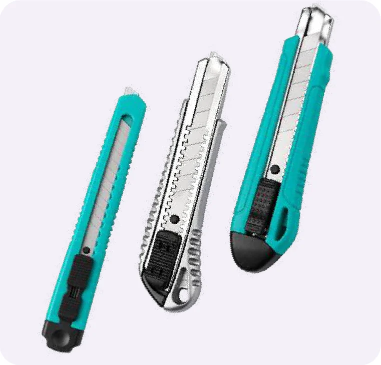 Tres cutters con la hoja asomando: uno angosto verde azulado, uno plateado de metal y uno ancho verde azulado con punta negra