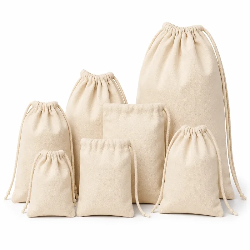Siete bolsas de lienzo natural con cordón (ahorque) de distintos tamaños, agrupadas sobre fondo blanco